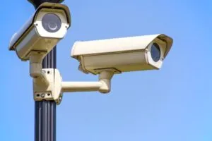 Câmaras de segurança exteriores montadas num poste contra um céu azul claro, assegurando uma vigilância atenta.