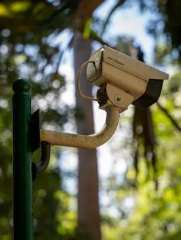 公園の緑のポールに取り付けられた監視カメラのクローズアップ。